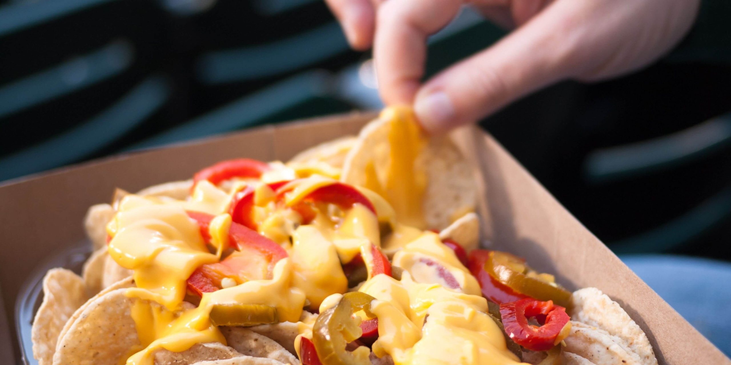 Hand lifting a nacho from a plate of nachos on National Nacho Day