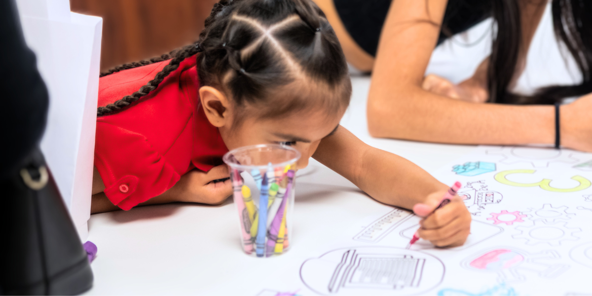 A young girl works intently on a hands-on STEM project, demonstrating curiosity and determination as she builds and experiments with creative solutions.