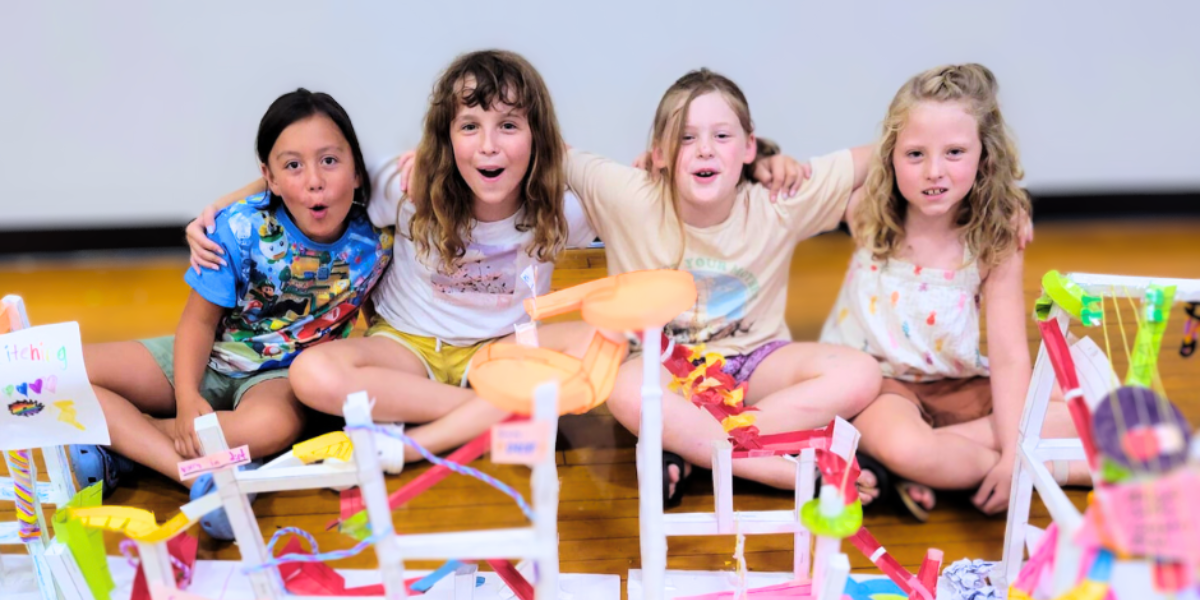 A joyful group of young girls cheers as their collaborative engineering experiment achieves success, showcasing the power of teamwork and creativity in STEM fields.