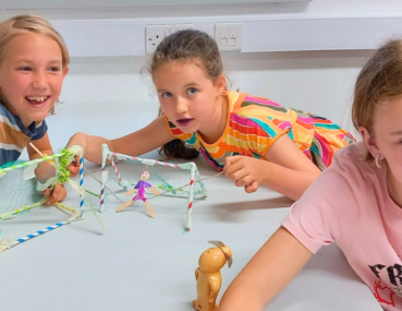 A lively group of girls explores STEM concepts through hands-on experiments, combining learning and laughter in an engaging environment.