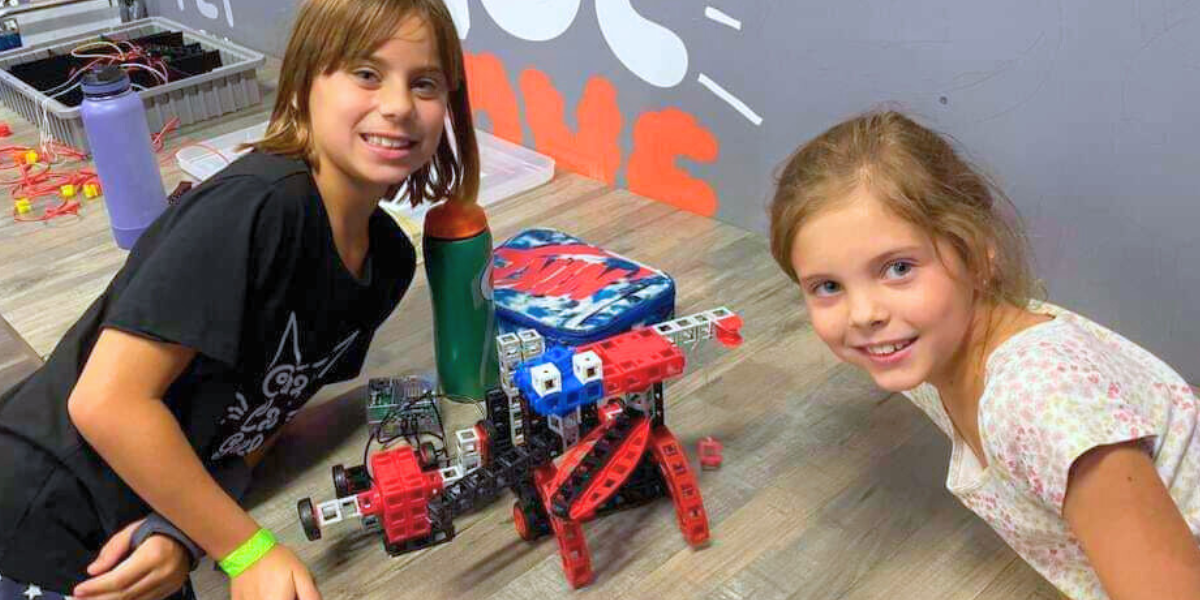 Two focused children carefully assemble parts of a robot, using tools and materials to bring their creation to life. This hands-on activity sparks creativity and introduces the basics of robotics engineering.