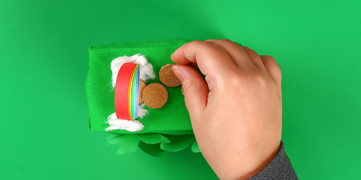 The third step in building a leprechaun trap, focusing on decorating the trap with natural-looking elements like rainbows, gold coins, and glitter to attract the leprechaun.