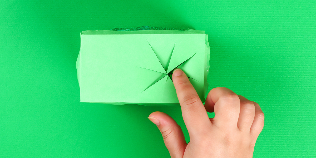 The second step in constructing a leprechaun trap, featuring a carefully crafted hole in the box designed to capture the mischievous leprechaun.