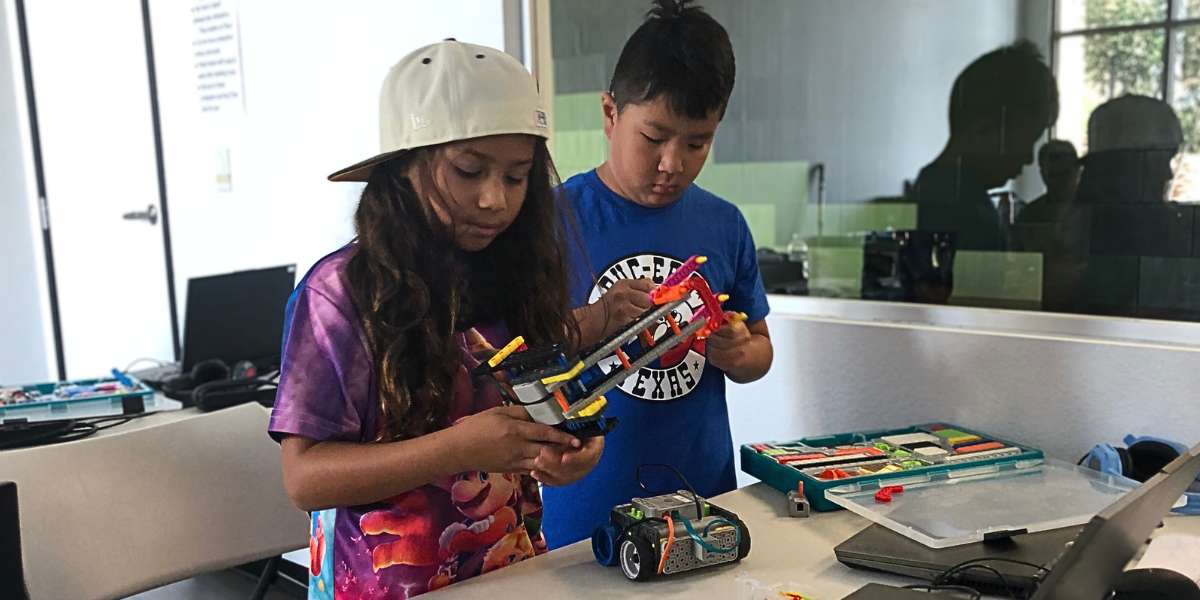 Two kids assembling a robot as part of a STEM activity, applying critical thinking and teamwork to solve engineering challenges.