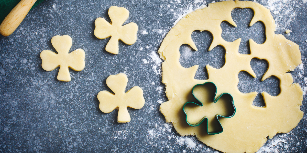 Freshly baked, green shamrock-shaped cookies decorated with icing, a perfect kid-friendly St. Patrick's Day activity for families who love baking together.